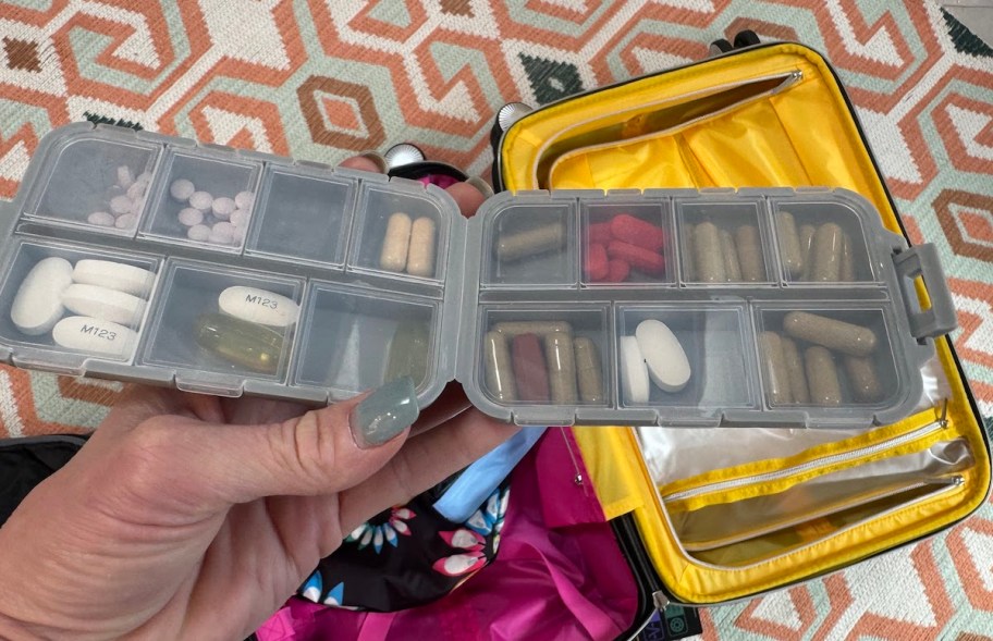 pill organizer over open suitcase on floor