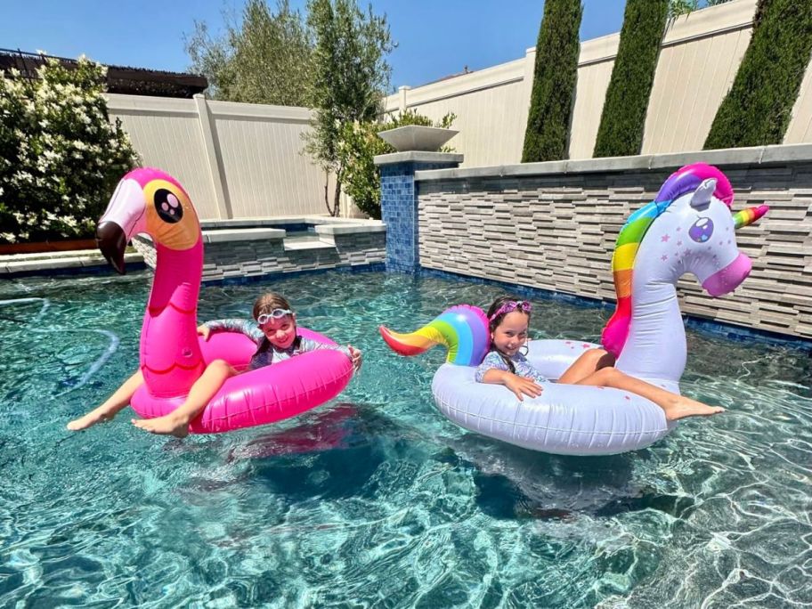 kids sitting a flamingo and a unicorn pool float in a pool