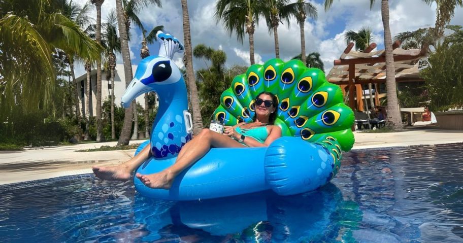 woman laying on peacock pool float in water