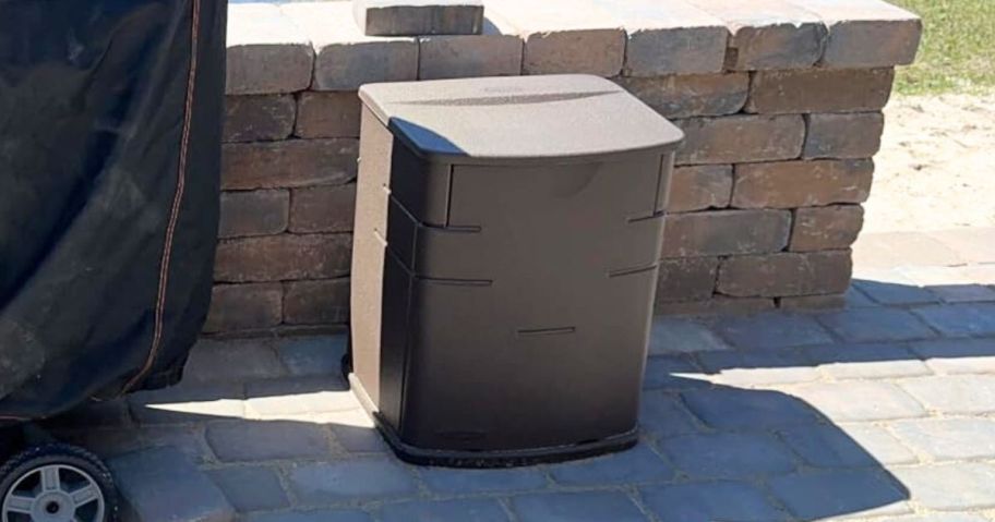 brown Rubbermaid 19-Gallon Small Resin Outdoor Storage Deck Box on patio against brick wall next to grill