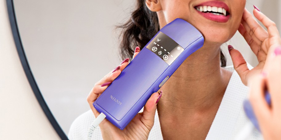 woman using purple laser hair remover on face