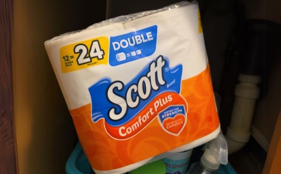 a 12 pack of scott comfort plus toilet paper stored under a bathroom sink