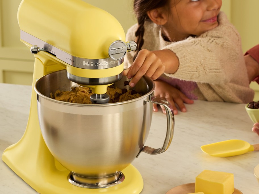 yellow butter mixer with child helping make cookies