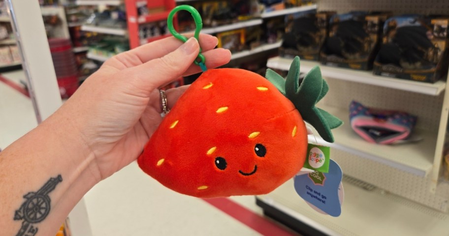 hand holding a strawberry plush clip on in a store