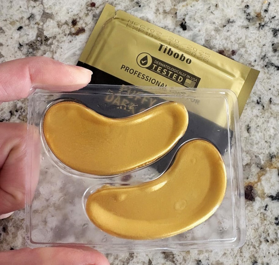 hand holding a pack of gold eye masks