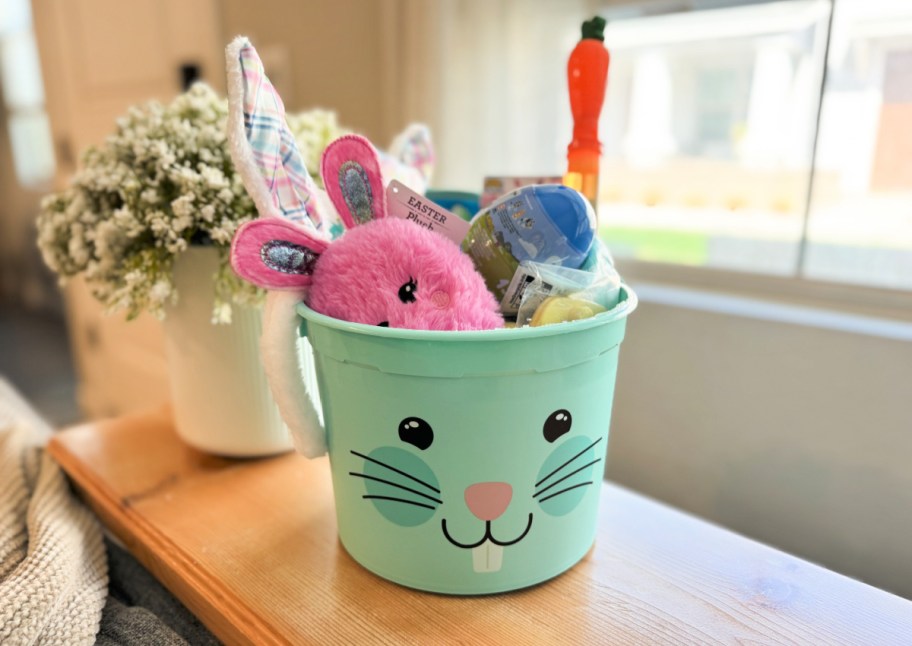 bunny-faced easter basket filled with small toys and games, sitting on the table next to a window