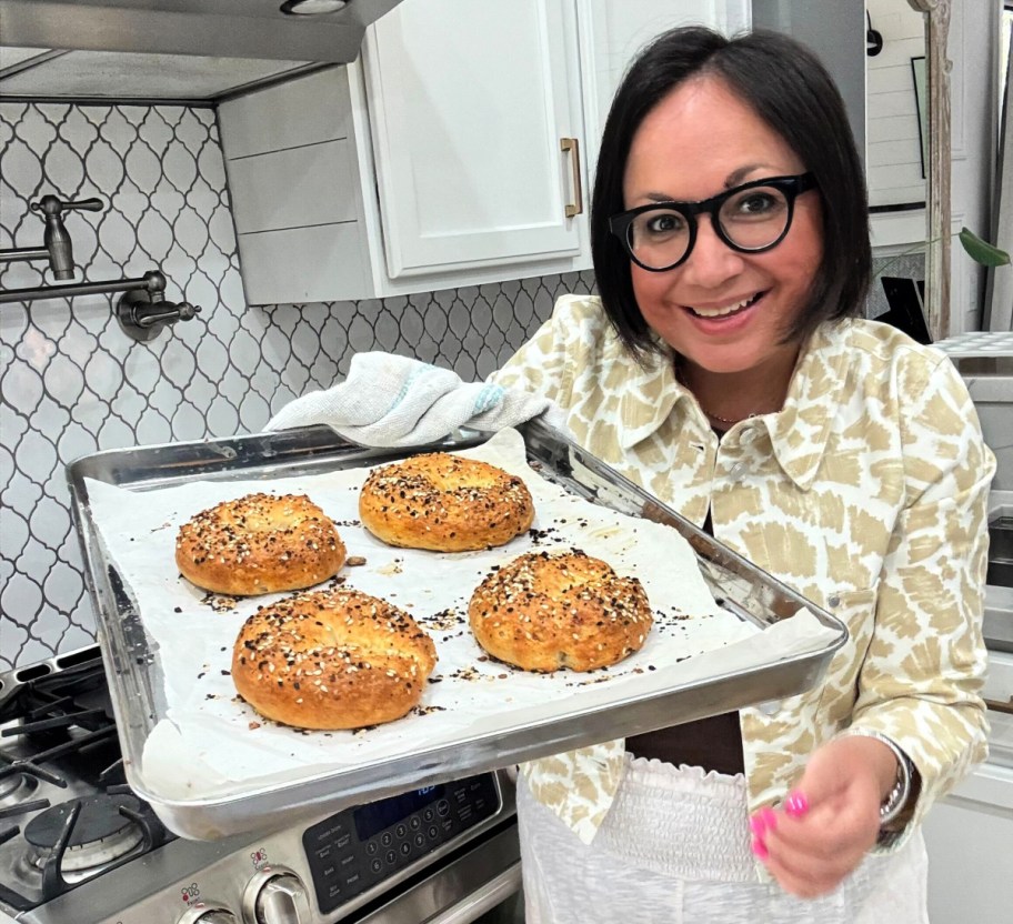 woman holding a tray of cottage cheese bagels after baking