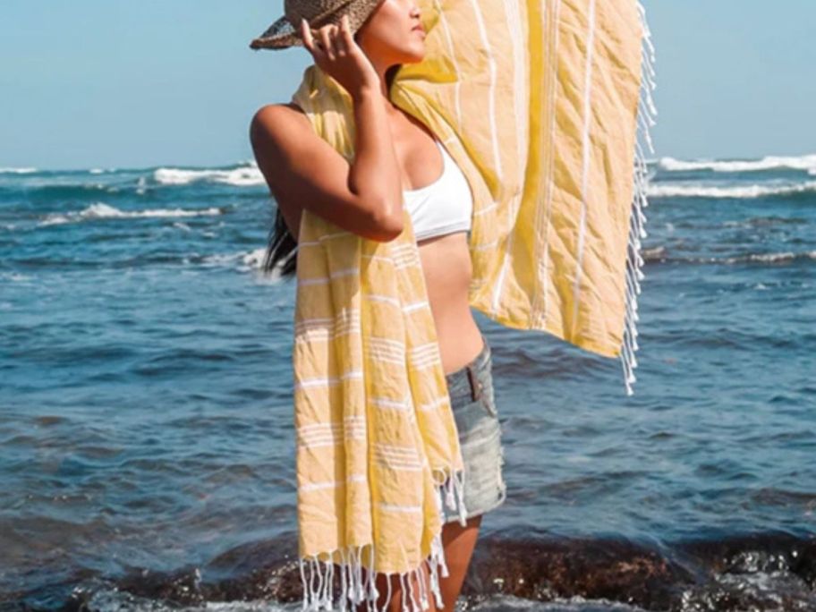 A woman wearing a yellow Turkish towel on a beach