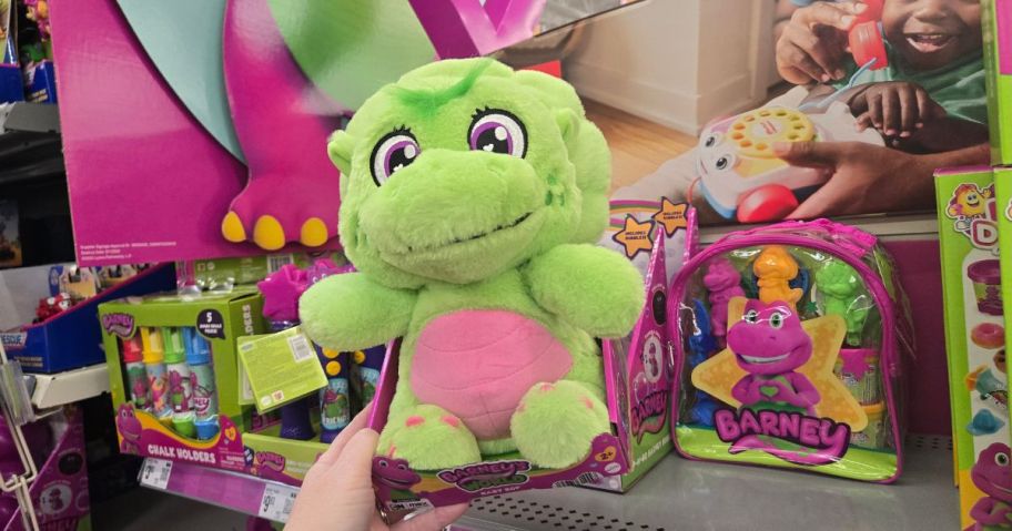 A person holding a Barney Baby Bop Plush toy