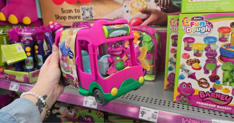 A person holding a Barney Bus playset