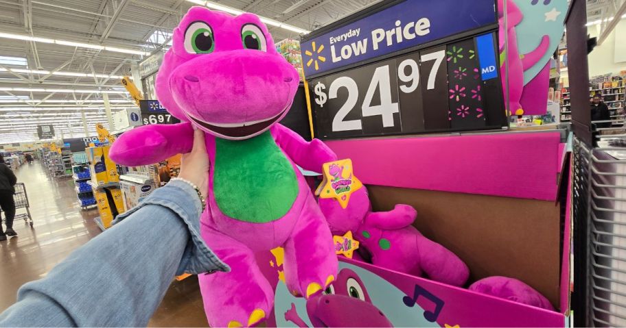 A person holding a large Barney Plush toy