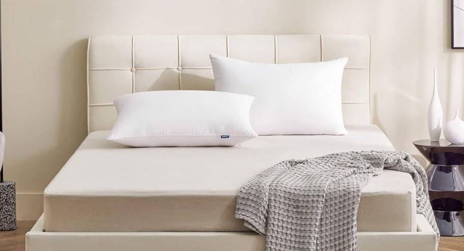 bed showing queen size hotel pillows with a blanket at the end of the bed