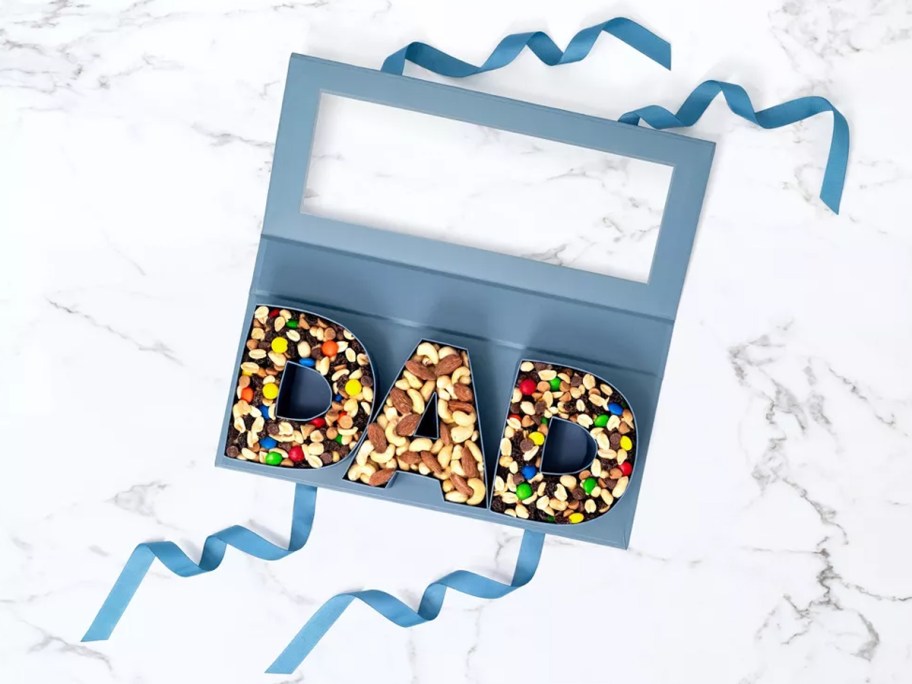 blue letters that spell out "dad" filled with trail mix in a blue gift box