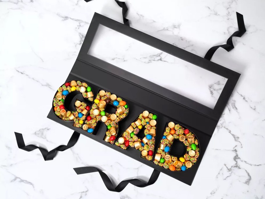black letters that spell "grad" filled with candies in a black gift box