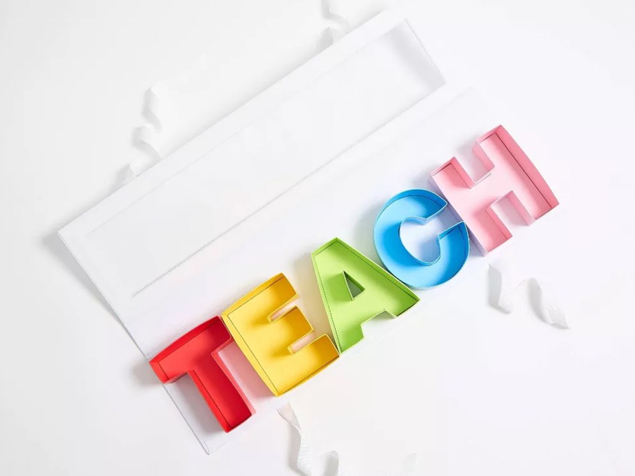 colorful paper letters that spell out "teach" with a gift box