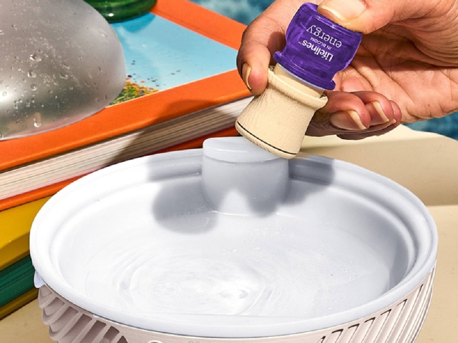 Hand dropping essential oil into diffuser