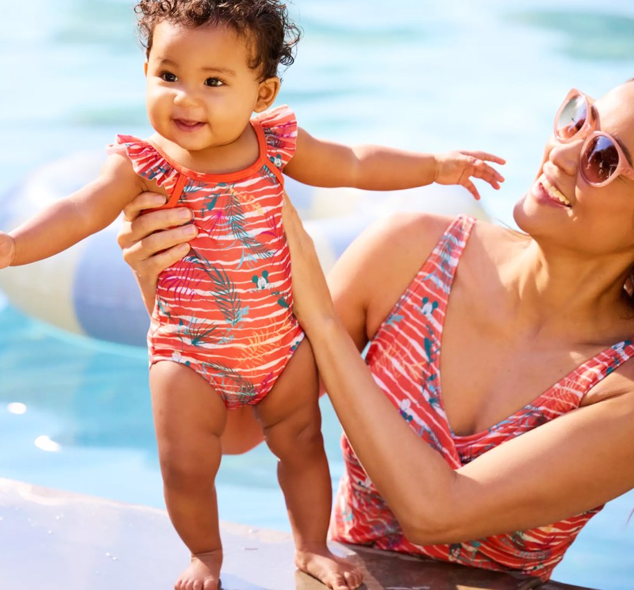 mom holding baby wearing matching orange swimsuits
