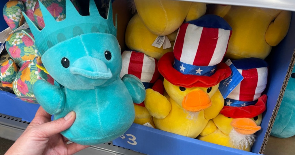 Person holding up small blue patriotic duck plush inside Walmart store