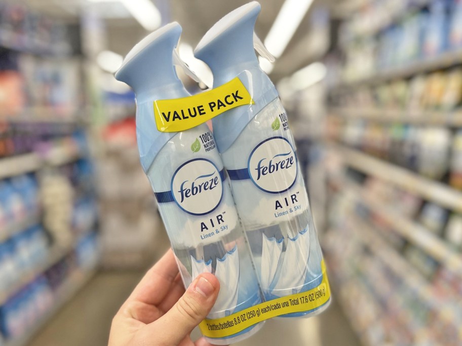 hand holding up a Febreze Linen & Sky Air Freshener Spray 2-Pack in store