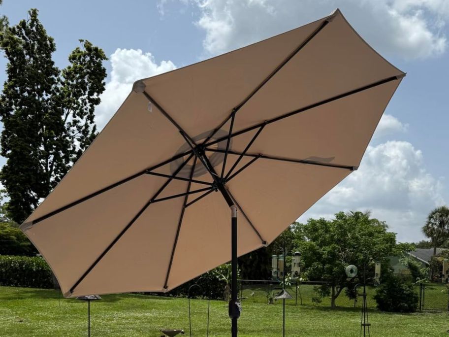 A tan patio umbrella opened attached to a table 