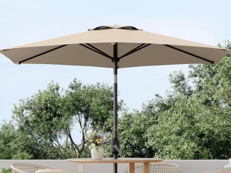 A tan patio umbrella opened attached to a table 