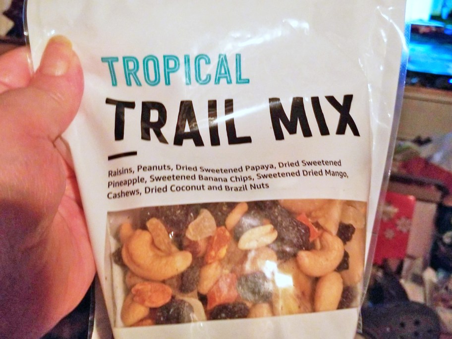 hand holding a bag of Happy Belly Tropical Trail Mix
