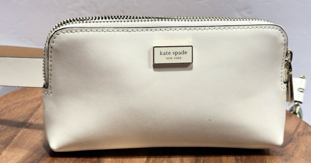 Cream colored Kate Spade bag on wooden table top