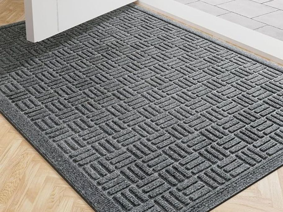 A grey doormat in front of an open door 
