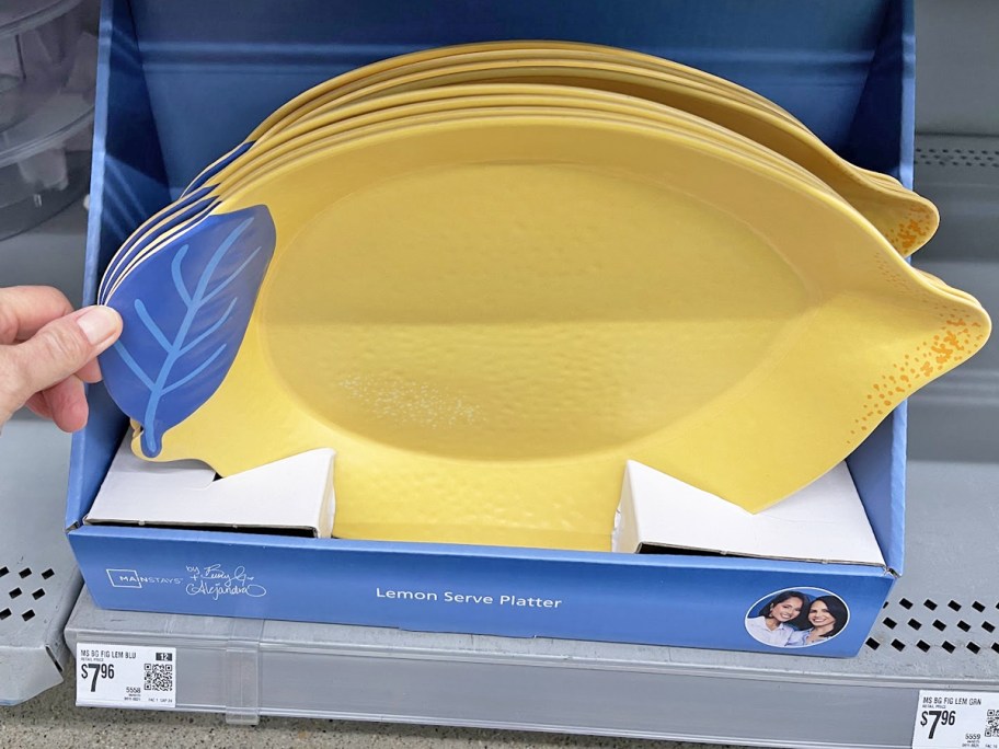 hand touching a display of lemon-shaped serving platters in store