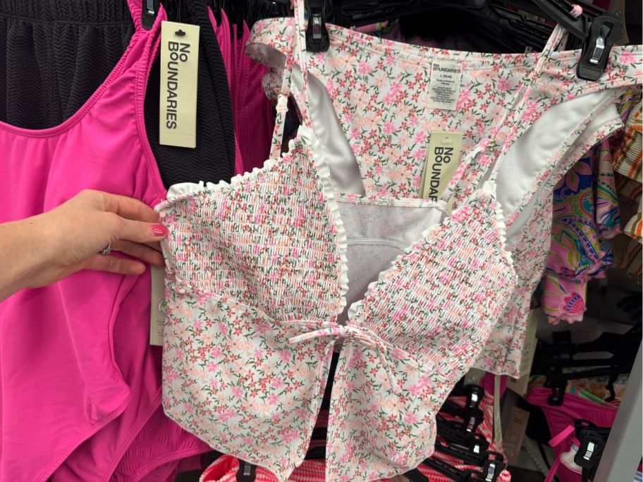 a womans hand holding a flora print 2 piece swimsuit