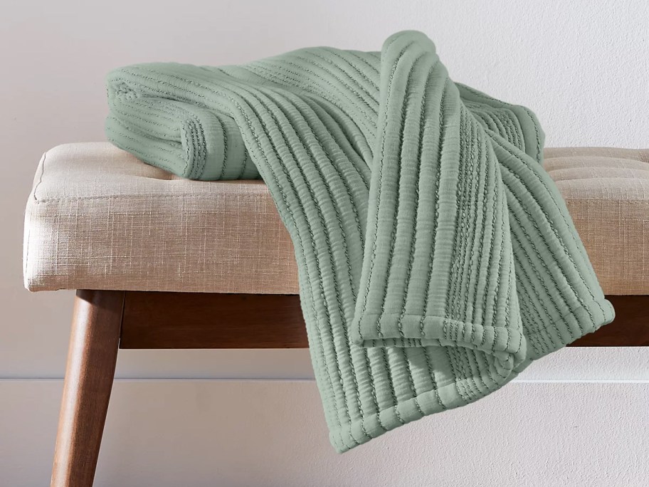 green ribbed throw blanket on a bench