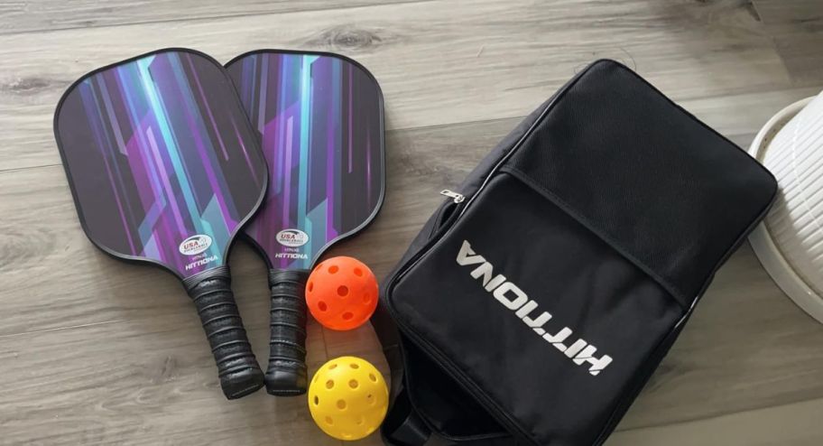 Two paddles with their carrying case and two balls plus a case next to it 