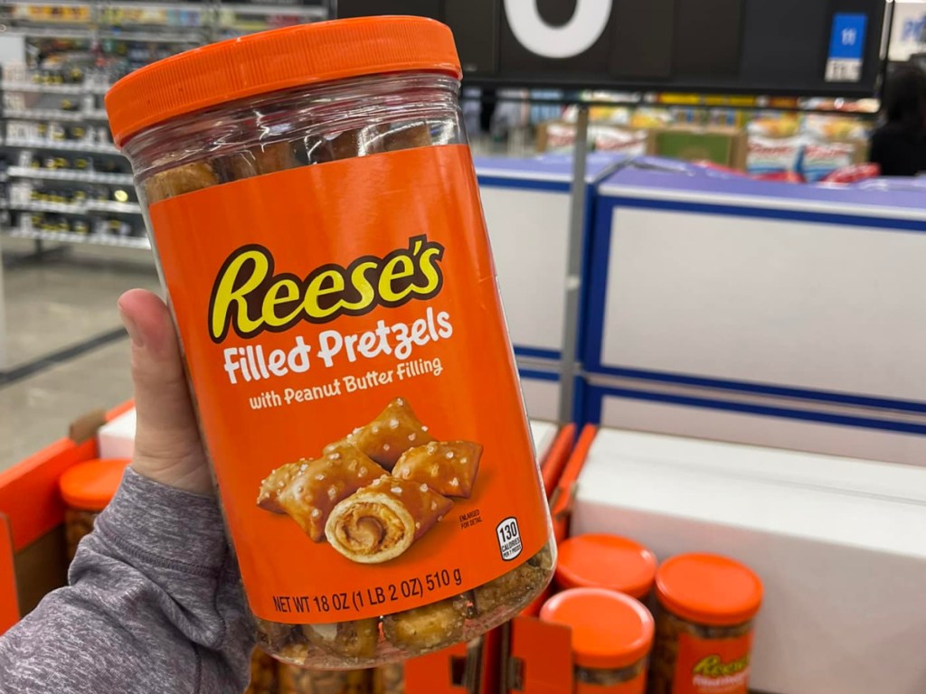 Woman holding up jar of Reese's filled pretzels in front of store display