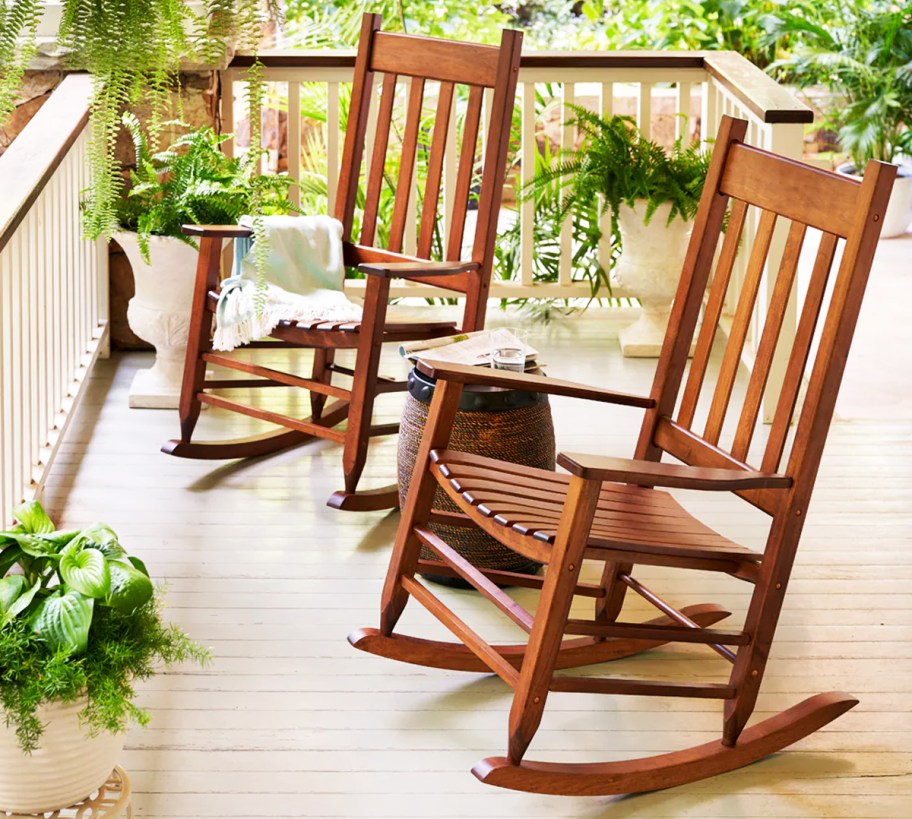 two wood rocking chairs on patio with lots of plants