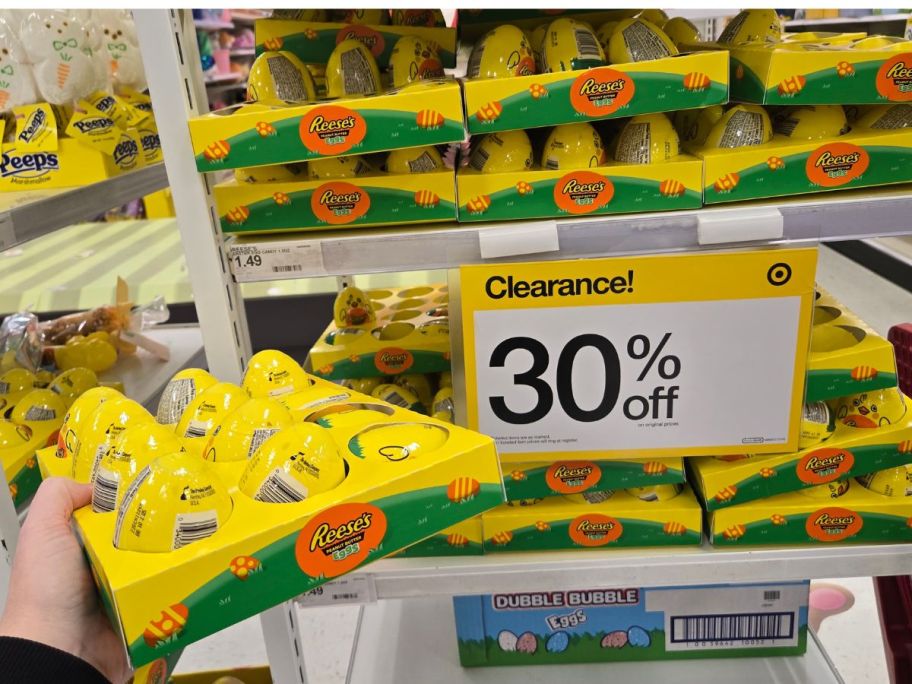 hand holding a box of Reese's Peanut Butter Candy Pre-Filled Easter Eggs next to a 30% off clearance sign