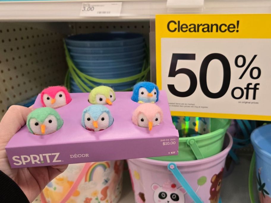 Hand holdin a Spritz Featherly Friends 6-Count Fabric Birds w/ Egg Carton Set next to a 50% off clearance sign 