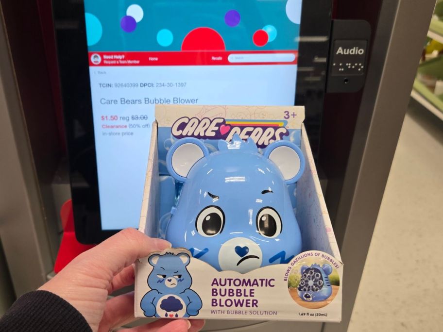 hand holding a care bears bubble blower in front of a target price checker