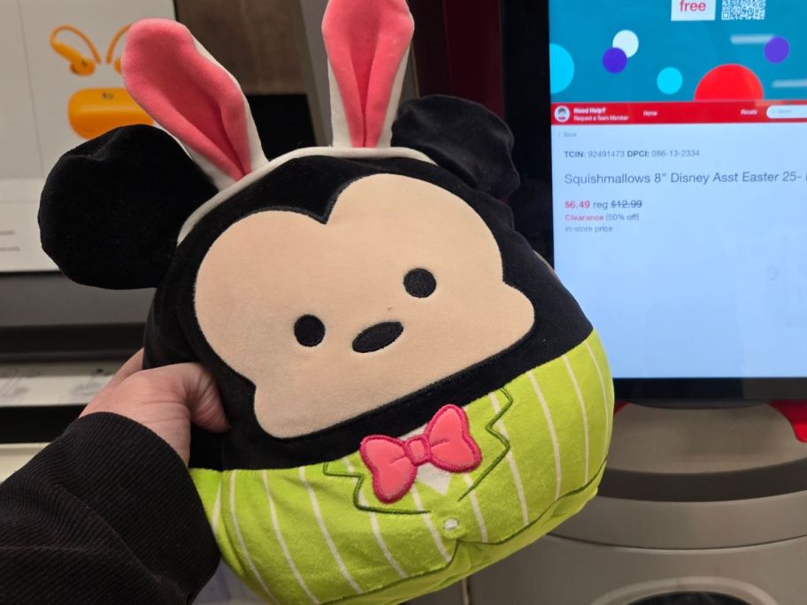 Hand holding a Mickey Mouse Squishmallow with bunny ears and a bow tie