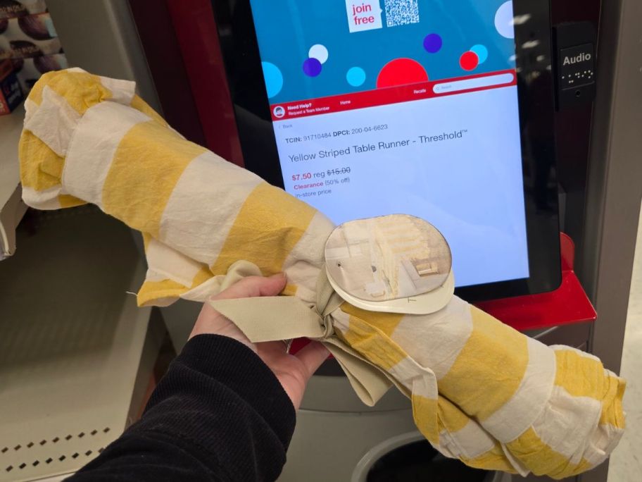 hand holding a Threshold Yellow Striped Table Runner in front of a Target price checker