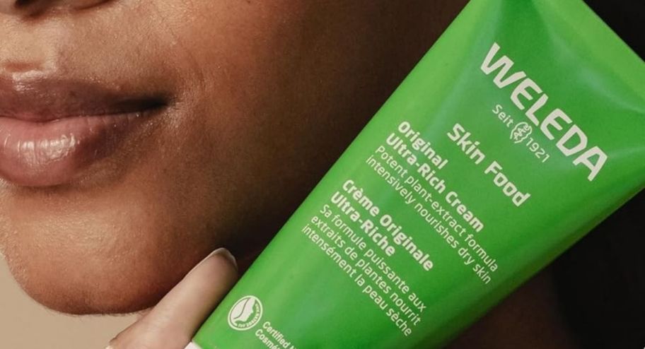 Woman holding a weleda skin lotion next to her face