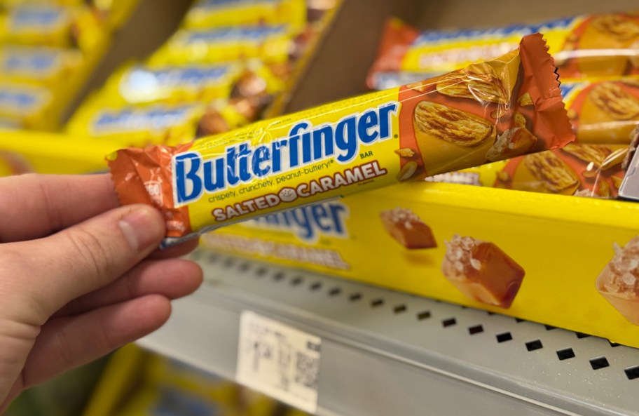 hand pulling a butterfinger salted caramel chocolate bar off a walmart store display