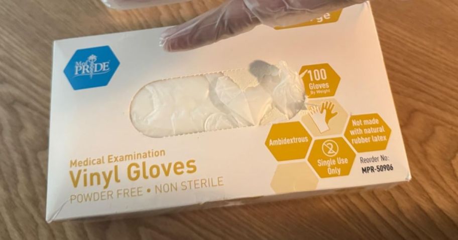 vinyl glove box on table with hand above it wearing glove