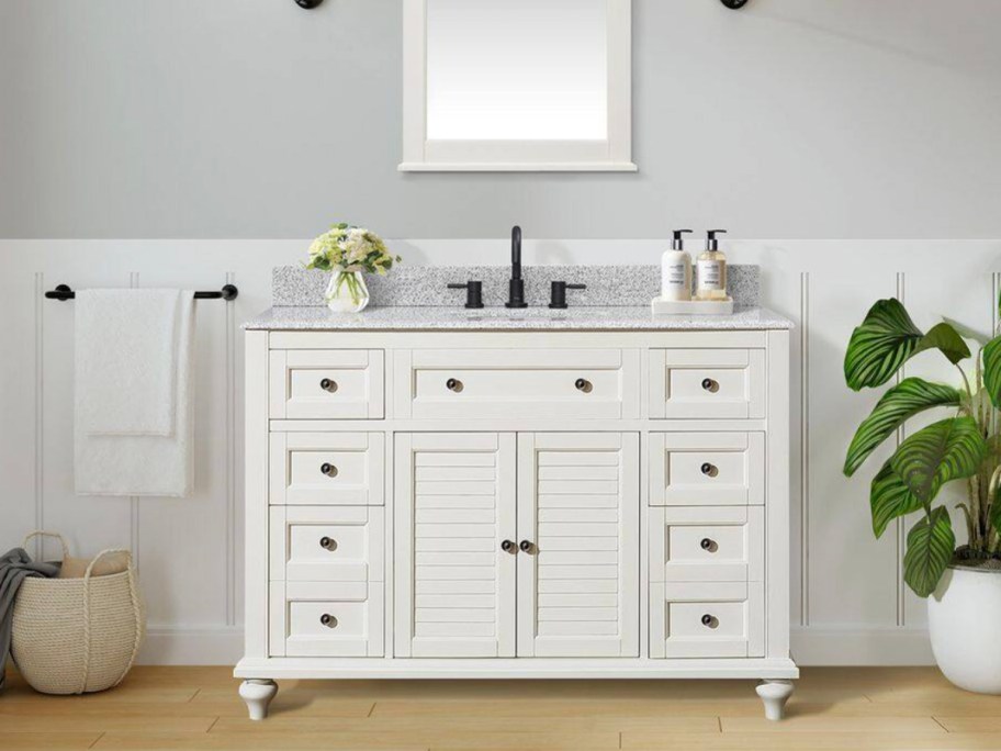 white bath vanity with mirror hanging about it 