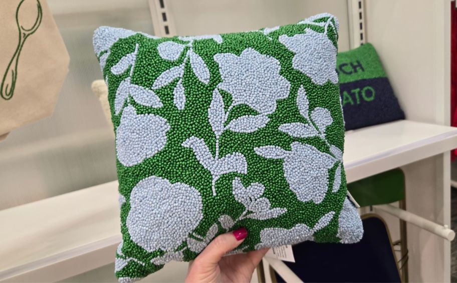 womans hand holding a square beaded floral print pillow
