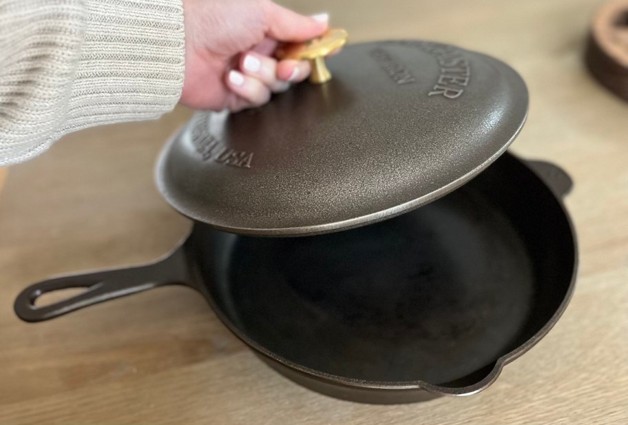 hand holding brass handle of cast iron pan