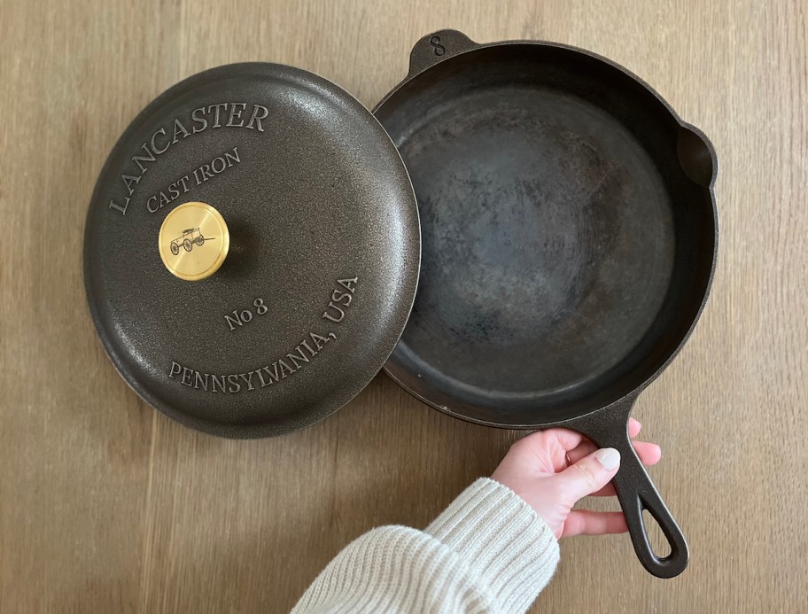 hand holding handle on lancaster cast iron pan on wood table