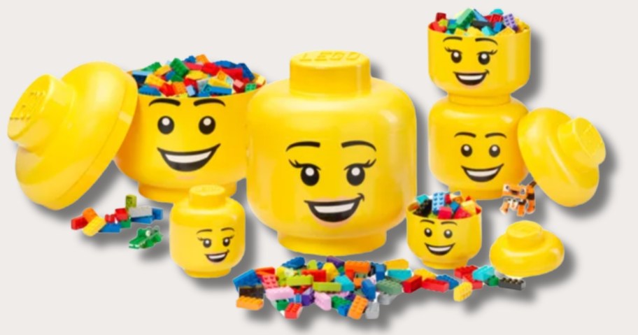 large, medium, and small LEGO head storage containers and LEGO's laying around them