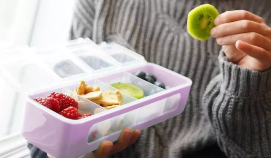 woman holding a pink melii snackle box and a kiwi slice