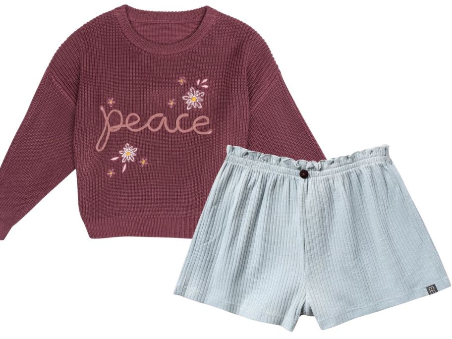 a pink modern moments sweater that says peace on it and light blue shorts
