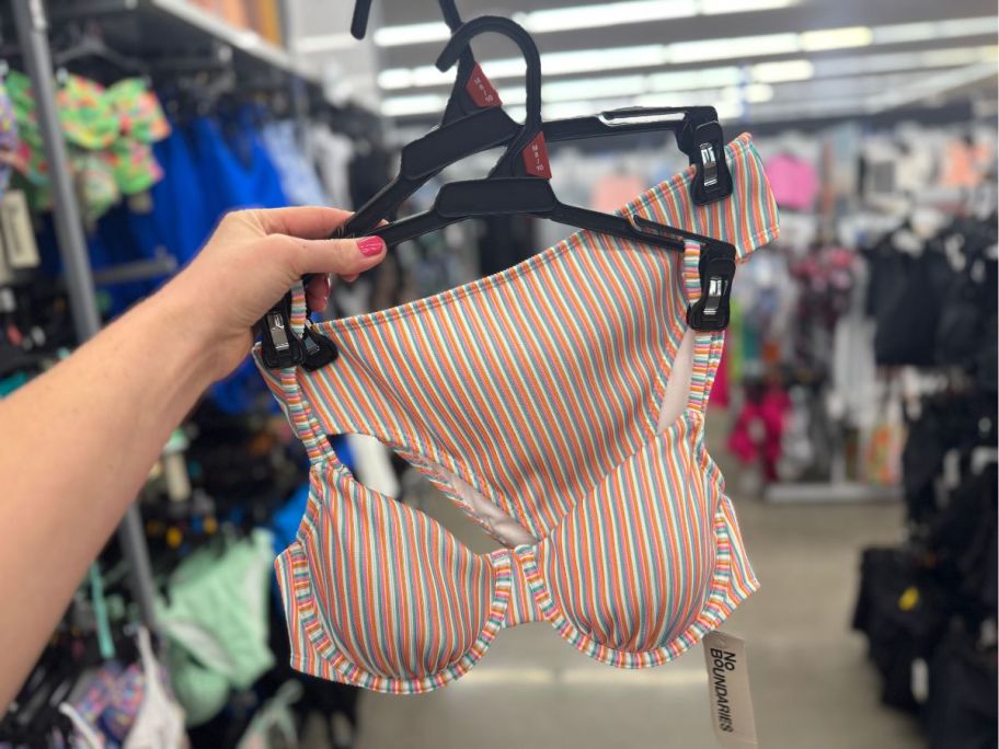 a womans hand holding a striped 2 piece swimsuit